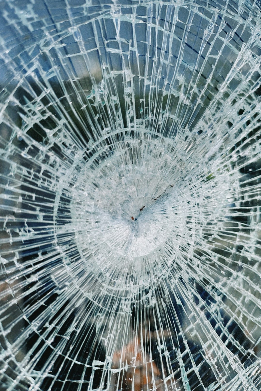 a broken glass window with a clock on it