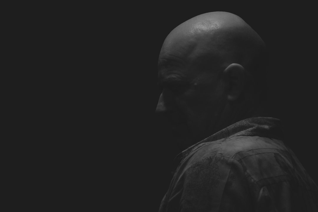 a man with a bald head standing in the dark